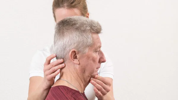 Une physiothérapeute positionne la nuque d'un patient.