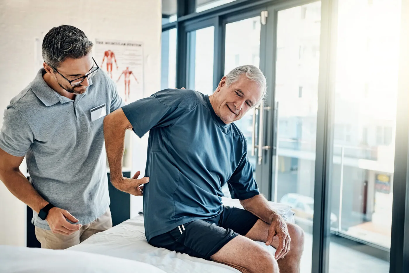 Physiotherapy, Chiropractor And Senior Man With Back Pain For Rehabilitation, Consulting And Exercise. Healthcare, Physical Therapy And Person With Patient For Medical Service, Wellness And Support
